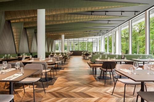 a restaurant with tables and chairs and large windows at Hotel Dolce La Hulpe Brussels in La Hulpe