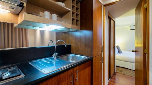 a kitchen with a sink and a room with a bed at Stay Essential Apartments by Time Hotel & Apartments in Santiago