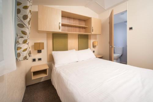 ein Schlafzimmer mit einem weißen Bett und einem WC in der Unterkunft Sandaway Holiday Park in Combe Martin