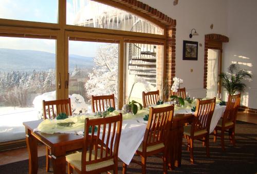 ein Esszimmer mit einem Tisch, Stühlen und einem Fenster in der Unterkunft Hotel Podlesí in Podlesí