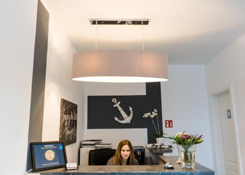 a woman sitting at a desk in an office under a light fixture at Hanse Hotel Buxtehude in Buxtehude