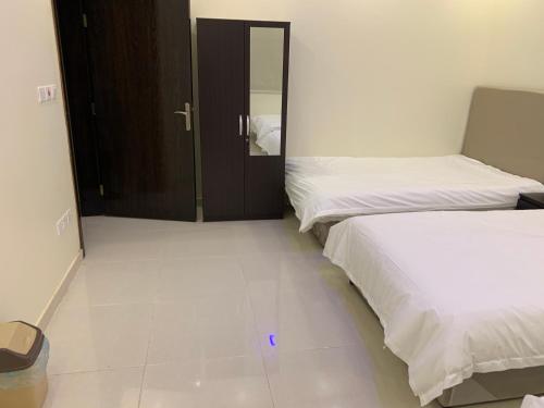 a bedroom with two beds and a door to a bathroom at Economic Homes Apartments in Yanbu