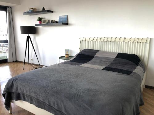 オーステンデにあるCosy, modern studio with an awesome view of Ostendのベッドルーム1室(ベッド1台、黒とグレーの毛布付)