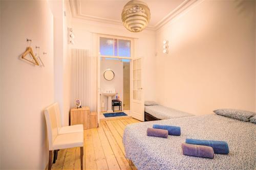 1 dormitorio con 2 camas, silla y ventana en The Greenplace Lodge. Apartment in Heart of Antwerp. en Amberes