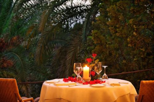 a table with a candle and red flowers on it at Alberi del Paradiso in Cefalù