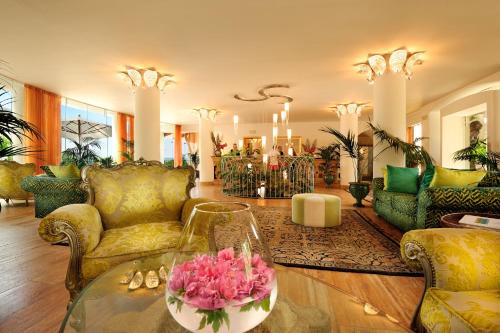 a living room with yellow furniture and pink flowers on a table at Alberi del Paradiso in Cefalù