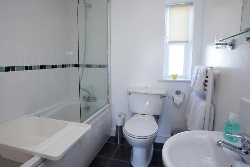 a white bathroom with a toilet and a sink at Ardnave in Port Charlotte