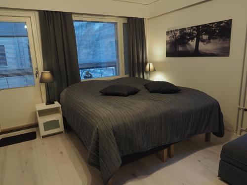 um quarto com uma cama com duas almofadas e duas janelas em Apartment Oulu station suite em Oulu