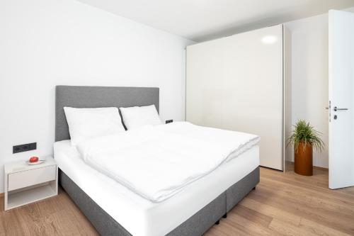 biała sypialnia z dużym łóżkiem z białą pościelą w obiekcie lake and mountains appartements w mieście Maishofen