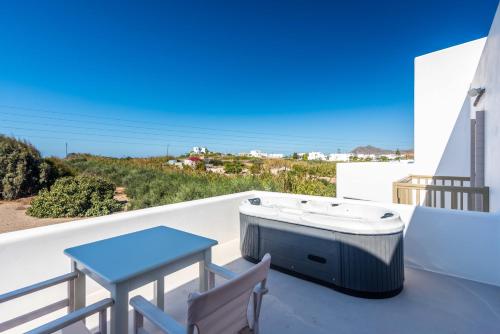 a hot tub on a balcony with a table and chairs at Milia Gi Suites in Pollonia