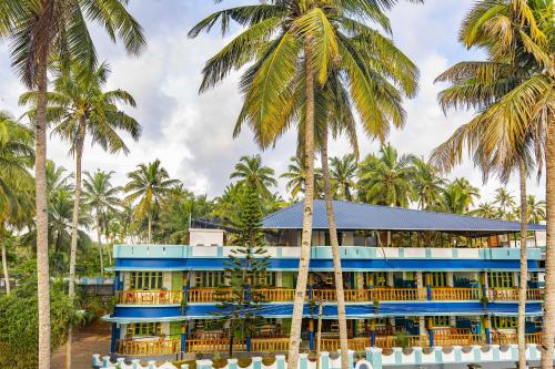 a blue building with palm trees in front of it at Zostel Varkala in Varkala