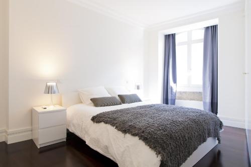 a white bedroom with a bed and a window at FLH Baixa Elegant Apartment in Lisbon