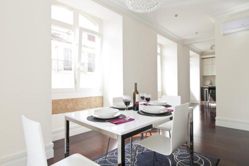 uma sala de jantar branca com uma mesa branca e cadeiras brancas em FLH Baixa Elegant Apartment em Lisboa