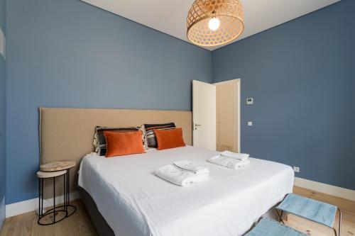 ein Schlafzimmer mit einem großen weißen Bett mit orangefarbenen Kissen in der Unterkunft FLH Cais Sodré Charming Flat in Lissabon