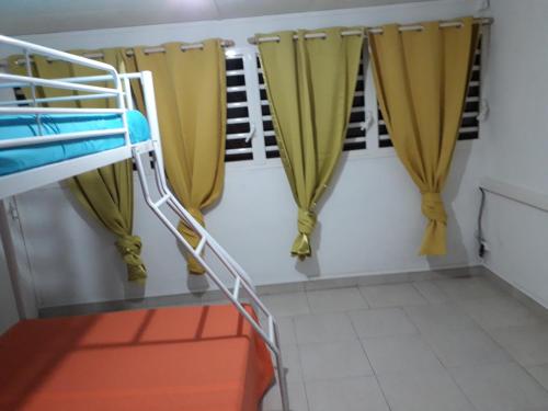 a bunk bed in a room with yellow curtains at F2 Mounacaz in Lamentin