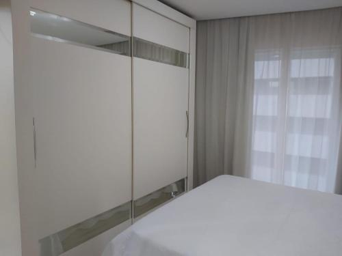una camera con letto bianco e specchio di Flat Parque Ibirapuera a San Paolo
