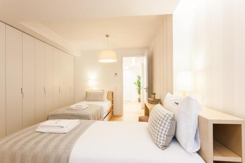 a white bedroom with two beds in a room at FLH Chiado Sunny Apartment in Lisbon