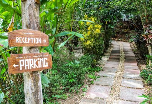a stone path in a jungle with signs on it at Lodge Margouillat in Tambor