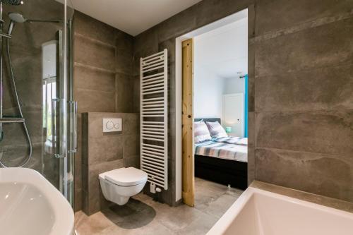 a bathroom with a sink and a toilet and a bed at Hofwestdijk in Vrouwenpolder