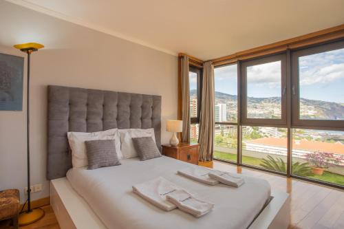 ein Schlafzimmer mit einem großen Bett und einem großen Fenster in der Unterkunft FLH Funchal Amazing Sea View Apartment with Pool in Funchal