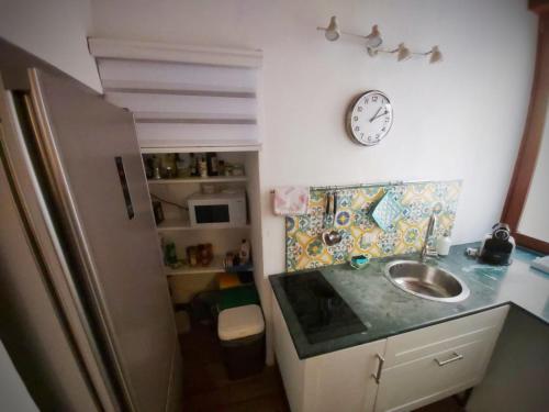 a kitchen with a sink and a clock on the wall at A Casa di Vale in Siracusa