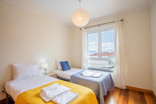 a bedroom with two beds and a window at FLH Funchal Modern Apartment with Pool in Funchal