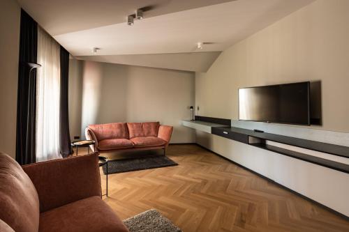 a living room with two chairs and a flat screen tv at Maestro Design Hotel in Liepāja