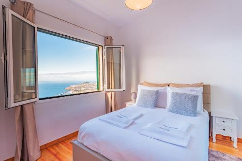 een slaapkamer met een bed en een groot raam bij FLH Funchal Ocean View with Pool in Funchal