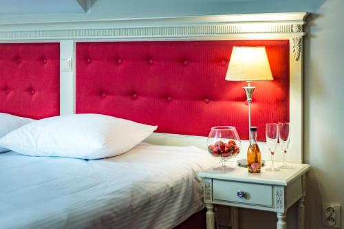 a bed with a red headboard next to a table with wine glasses at Hotel Sobienie Królewskie in Sobienie Szlacheckie