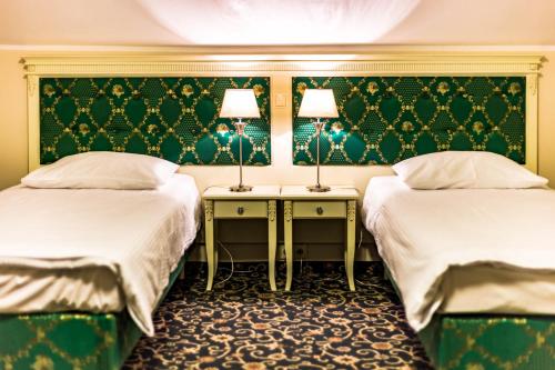 two beds in a room with green wallpaper at Hotel Sobienie Królewskie in Sobienie Szlacheckie