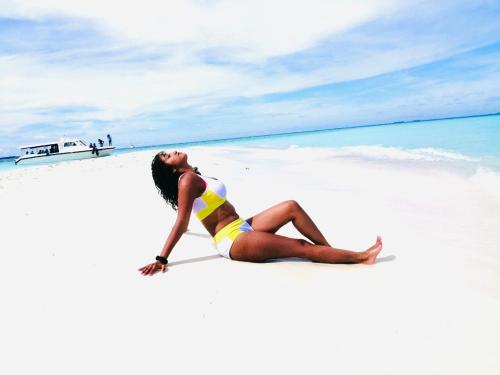 a woman is sitting on a beach at Maafushi View in Maafushi