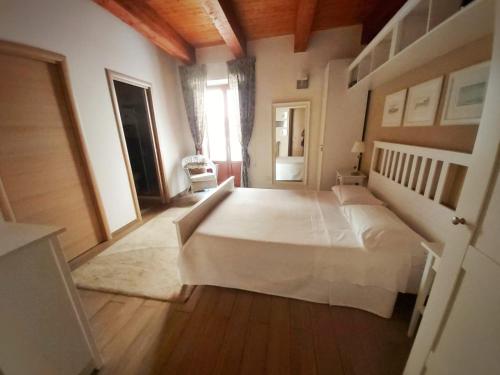 1 dormitorio con cama blanca y suelo de madera en A Casa di Vale, en Siracusa