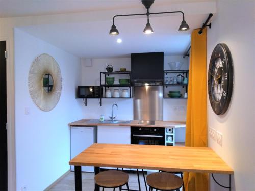 une cuisine avec une table en bois et quelques chaises dans l'établissement Superbe studio entre le port et le centre ville - LIT KING-SIZE, WiFi & NETFLIX gratuit, à Saint-Brieuc