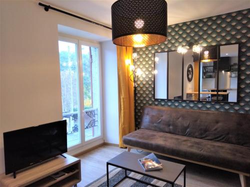 un soggiorno con divano in pelle e specchio di Superbe studio entre le port et le centre ville - LIT KING-SIZE, WiFi & NETFLIX gratuit a Saint-Brieuc