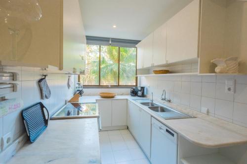 cocina blanca con fregadero y ventana en FLH Luxury Villa Mar with Private Sea Access, en Caniçal