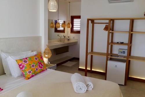a bedroom with a bed and a bathroom with a sink at Pousada Tartaruga Boutique Hotel in Pipa