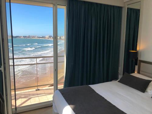 レ・サ​​ーブル・ドロンヌにあるHotel & Spa Les Roches Noiresのビーチの景色を望むベッドルーム1室(ベッド1台付)が備わります。