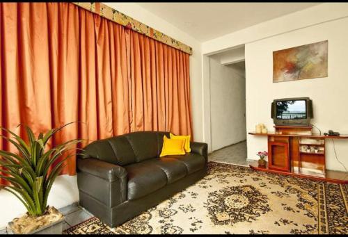 a living room with a leather couch and a television at Residencial Potengy in Natal