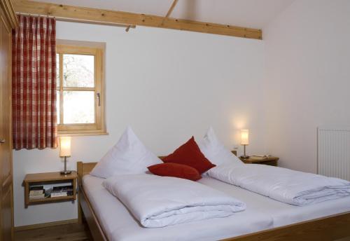 a bedroom with a bed with white sheets and red pillows at GolfAmGutshof18 in Bad Griesbach
