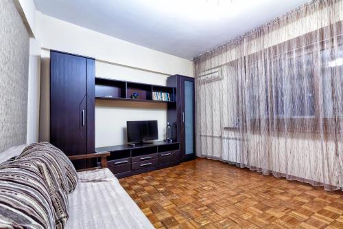Un dormitorio con una cama y un televisor y una ventana. en 32 Апартаменты в центре города - выбор для туриста и деловых поездок, en Almaty