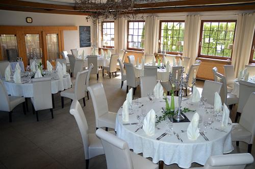 un comedor con mesas blancas y sillas blancas en Quartier-Restaurant Zum Hannes en Niederhausen