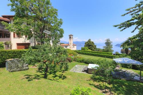 a garden with a house and an umbrella at Villa Rubino Apartment con giardino e jacuzzi vista lago in Stresa