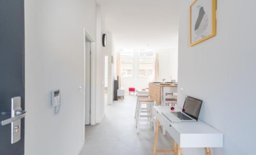 een witte woonkamer met een laptop op een bureau bij Séjour chez le Marin in Le Havre