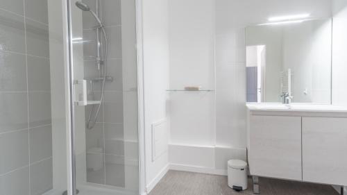 een witte badkamer met douche en wastafel bij Séjour chez le Marin in Le Havre