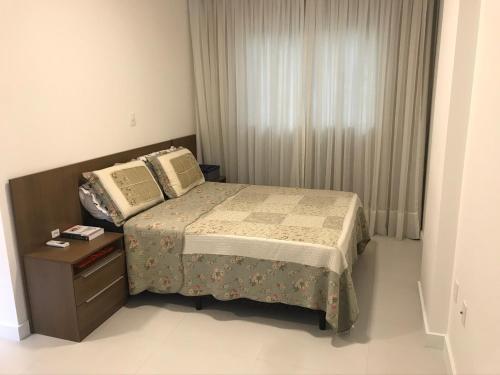 małą sypialnię z łóżkiem i szafką nocną w obiekcie Apartamento 2 dormitórios a 350 metros do mar na Meia Praia - Itapema-sc w mieście Itapema