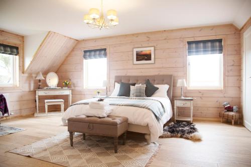 Netherton Farm Lodge في Kemnay: غرفة نوم بسرير كبير ونوافذ