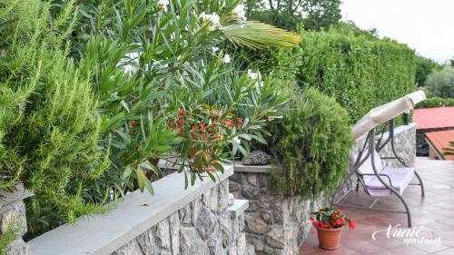 a stone retaining wall with plants and a bench at Apartments Vunić in Mošćenička Draga