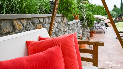 a white couch with red pillows on a patio at Apartments Vunić in Mošćenička Draga