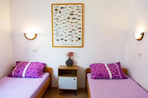 two beds in a room with purple pillows at Apartment Rino, only 30m from the sea in Pag
