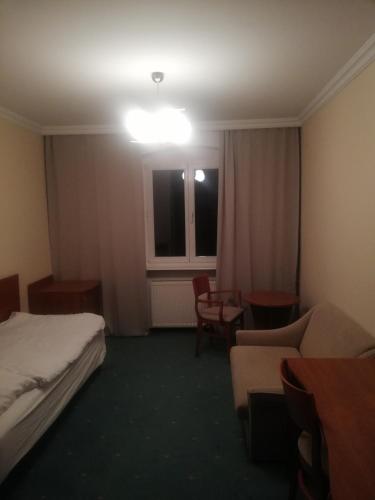 a hotel room with a bed and a couch and a window at Hostel Ratuszowy in Bydgoszcz